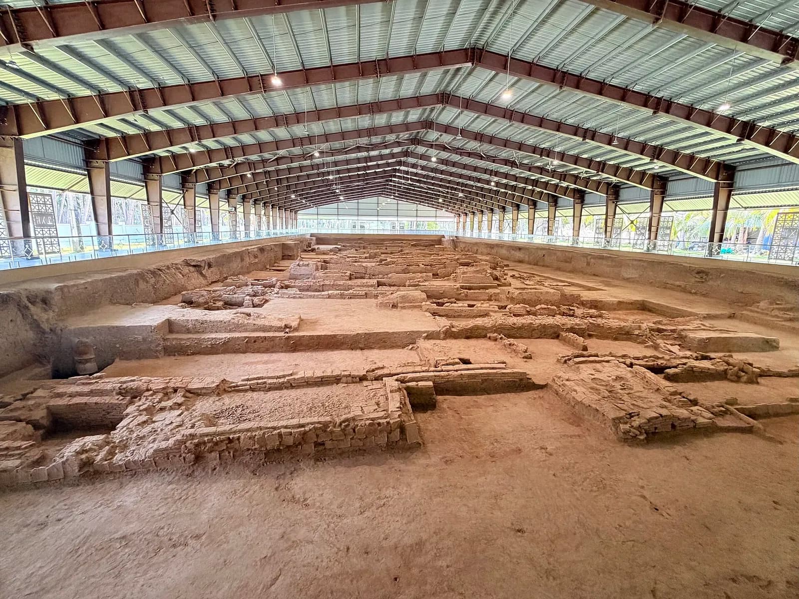 Excavated brick structures in open trenches under a shed at the Keeladi site