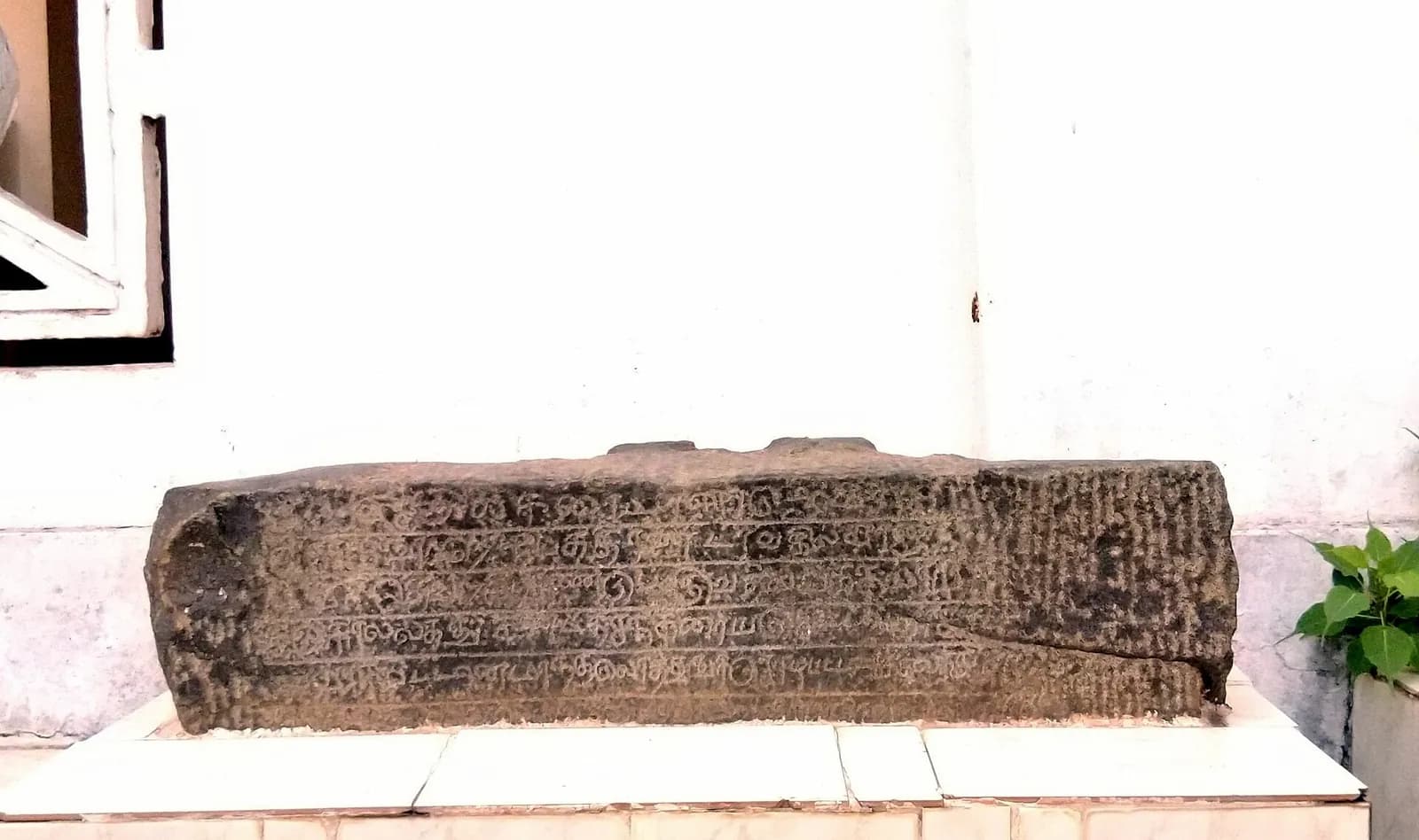 A weathered stone slab carved with rows of Tamil script, dated 1083 CE